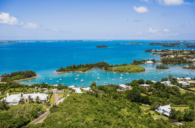 A scenic tropical bay dotted with boats and colorful houses along the shoreline.