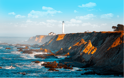 A scenic view of a lighthouse on a rocky cliff in Northern California, with the ocean in the background.