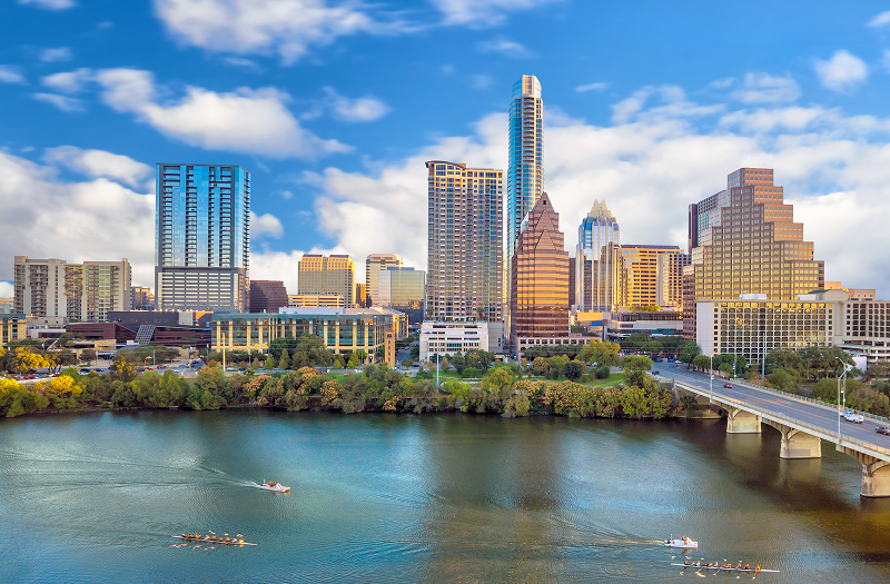 A view of Austin, TX skyline along the river with boats navigating the water.