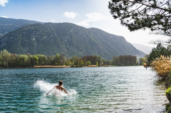 A man splashing into a blue mountainside lake