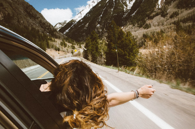 A woman hanging out of a car window enjoying the breeze