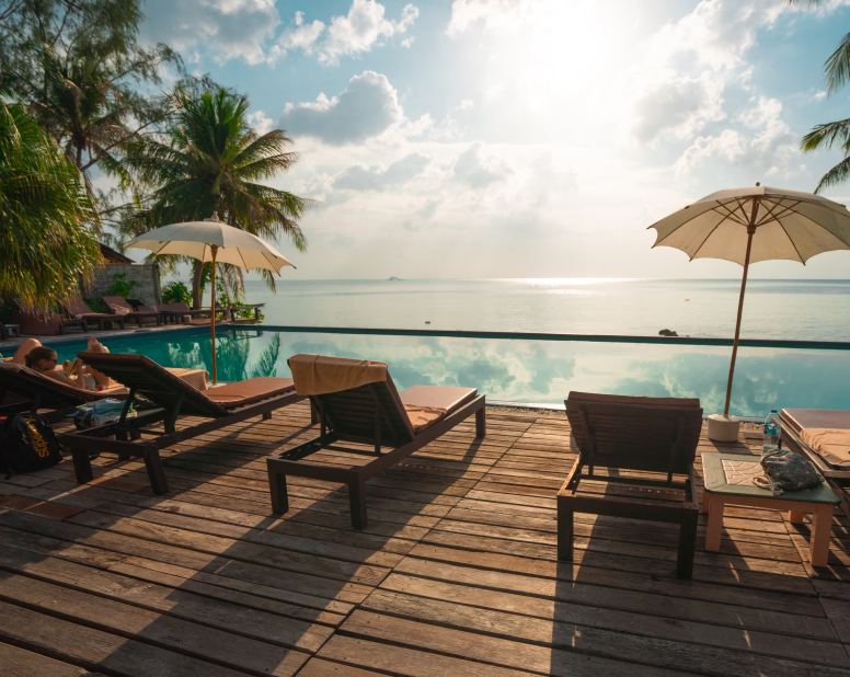 Deck chairs on a sunlit wooden deck overlooking a stunning ocean view