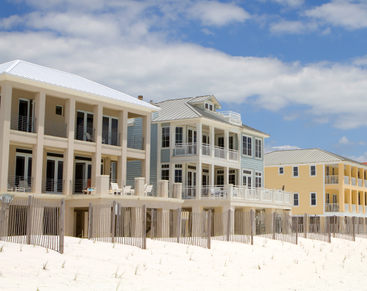 The rear of several beachfront buildings with white sands in the foreground