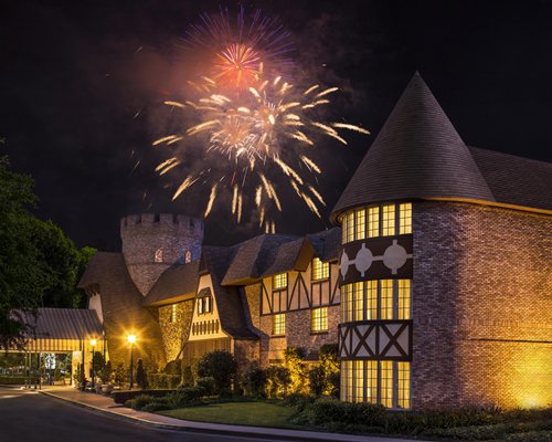 A night view of the exterior of the Anaheim Majestic Garden Hotel with fireworks in the sky above it