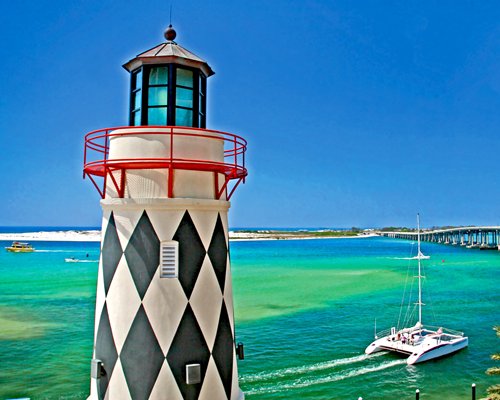 A model lighthouse in the foreground near the waters of Destin with a boat passing by