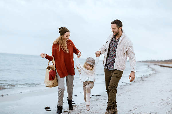 A family enjoying a chilly walk on the shore.