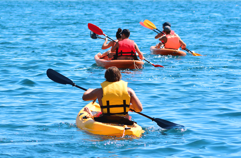 Five people kayaking along open waters on two red kayaks and one yellow kayak.