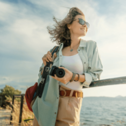A woman with a camera enjoying the sea breeze while exploring.
