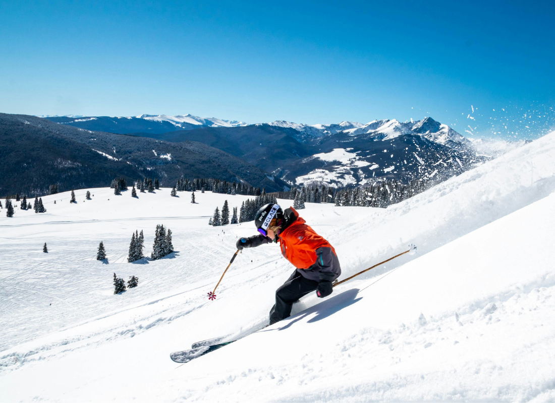 A person skiing down a snow mountain with a bright blue sky overhead.