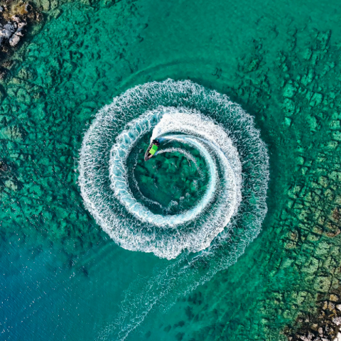 A person forming a circle in the shallow waters with a jet ski