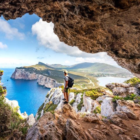 A man taking in the view on top of a rock during a hike.