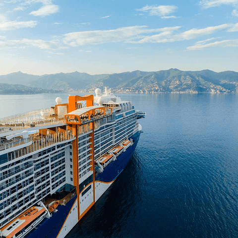 A large cruise ship sailing through the deep blue ocean under a clear sky.  