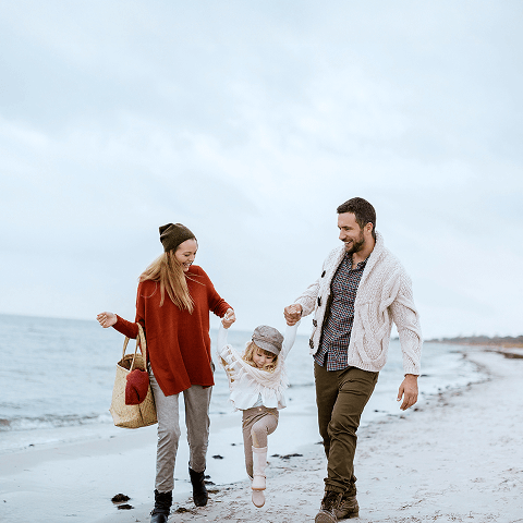 A family enjoying a chilly walk on the shore.