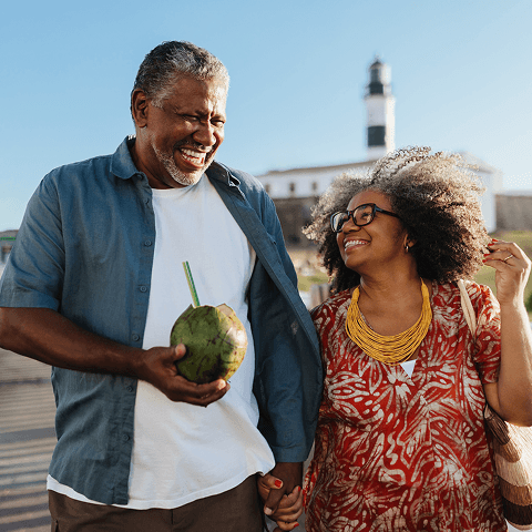 A man and a woman smiling happily as they walk together with a coconut drink in hand.