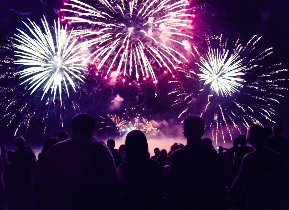 Many people standing together watching colorful fireworks fill the dark night sky.