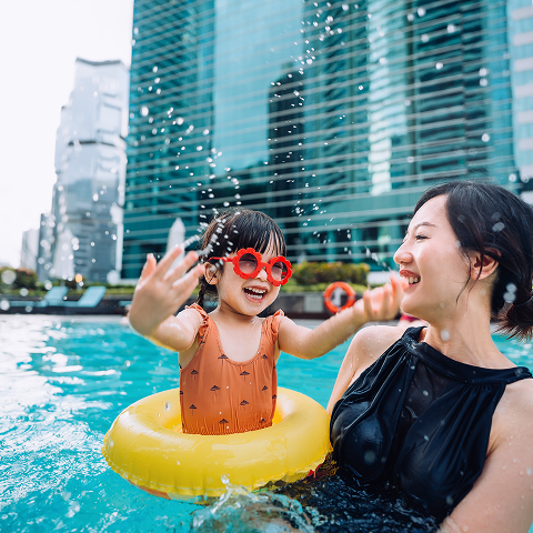 A woman and a child enjoying splashes at the pool.
