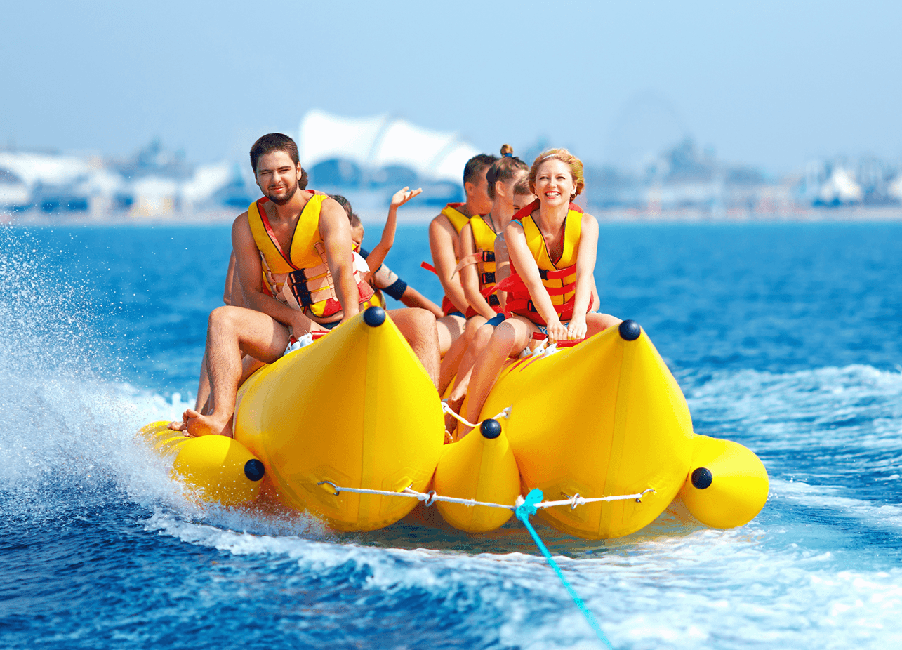 A happy group riding on an inflatable banana boat in the ocean.