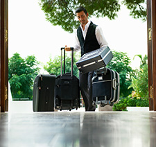 A bellman walking a number of suitcases into a hotel lobby