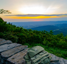 A beautiful scenic mountain at sunrise with a backpack on the ledge of the mountain