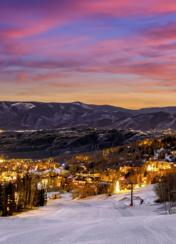 Snow covered streets of small town at sunset with mountains in the background