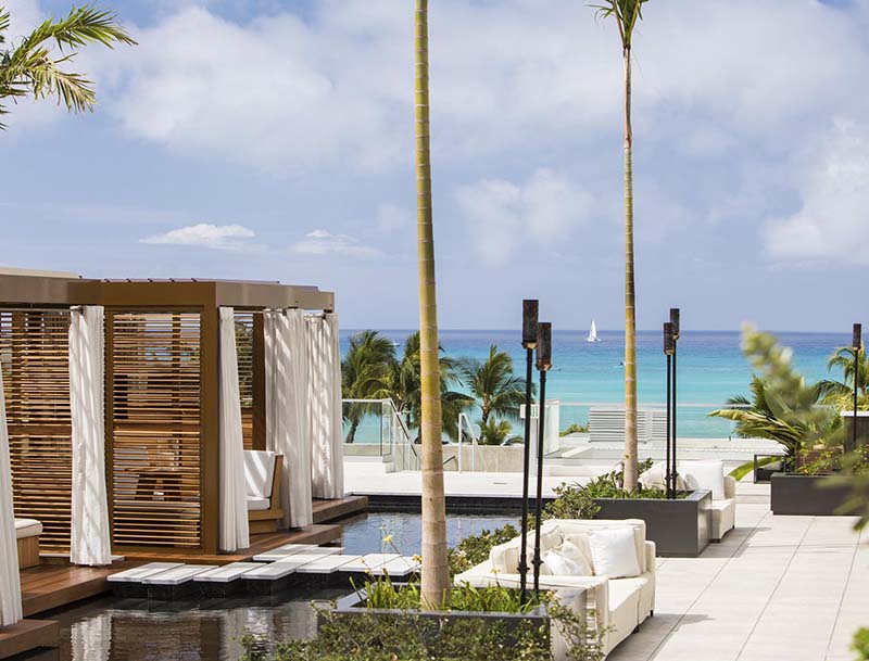 A scenic view of the ocean from the hotel patio featuring cabana seating and tropical landscaping.