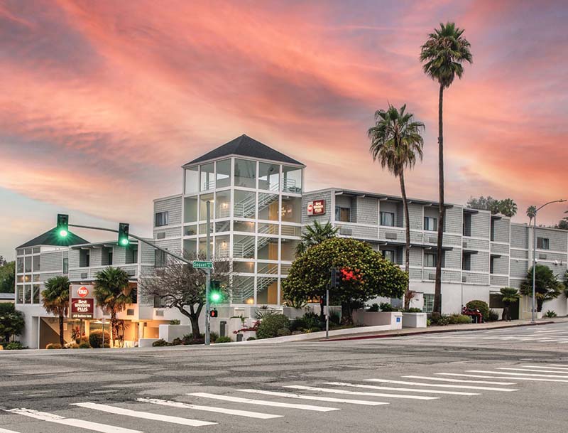 Exterior view of the hotel building against the backdrop of a colorful sunset sky.