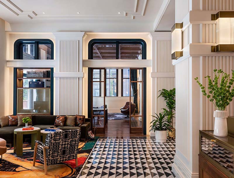 An elegant hotel lobby featuring cozy sitting areas and striking black and white tiled flooring.