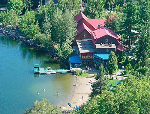 Aerial view of a lake and recreational area, surrounded by lush natural landscaping and tall trees.