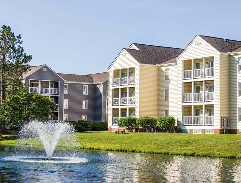 A view of the resort buildings situated next to a large water feature with a lively fountain.