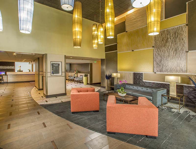 A bright, elegant hotel lobby featuring an inviting seating area and modern overhead lighting.