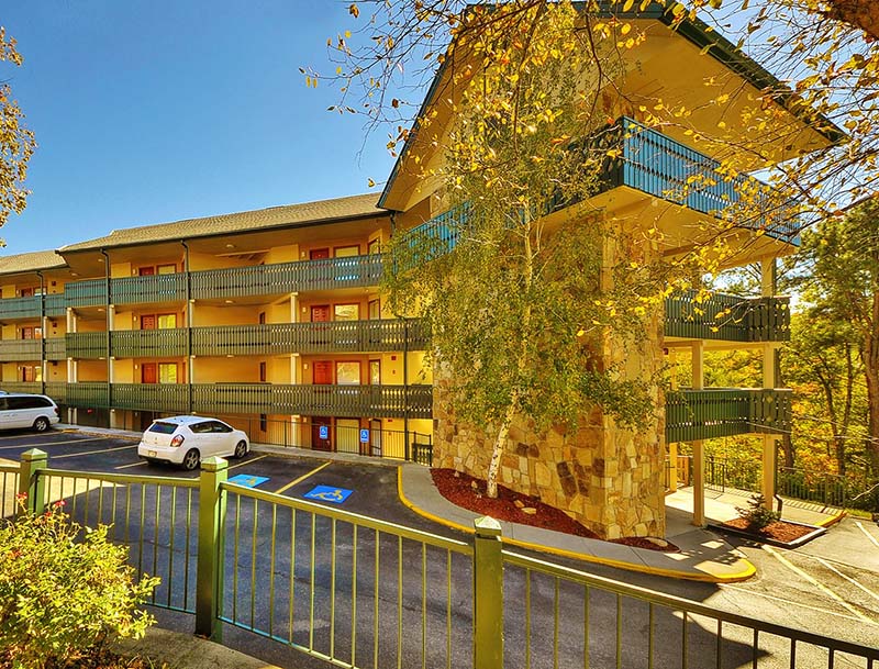 A sunlit view of the multistory resort building and surrounding autumn landscape.