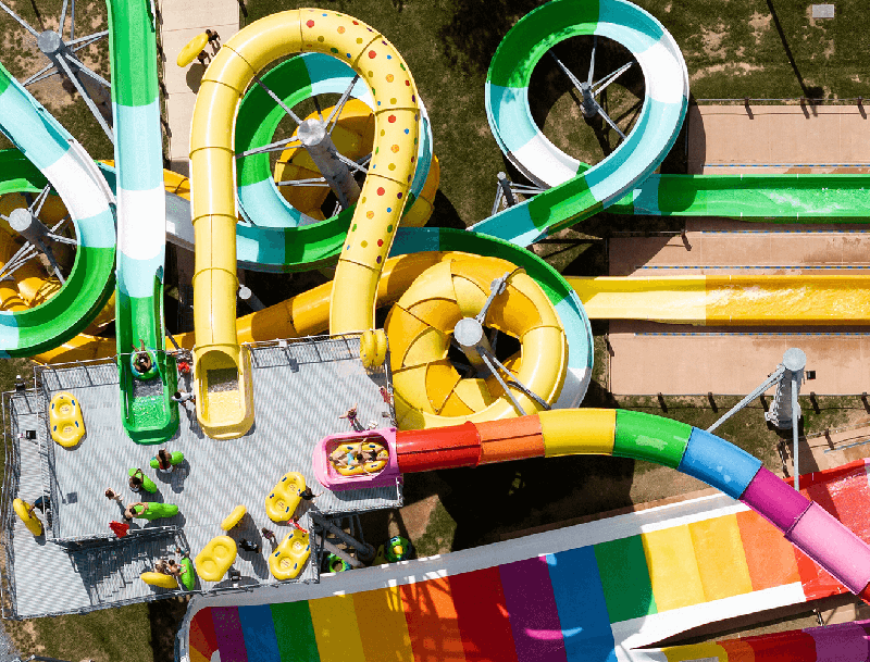 An overhead shot of a water park with guests enjoying the brightly-colored slides.