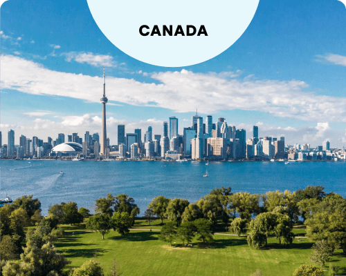 The Toronto, Canada skyline and CN Tower as seen from the tree-filled Toronto Islands across Lake Ontario.