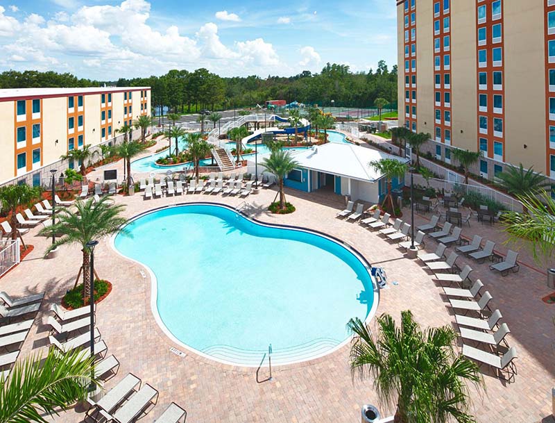Aerial view of the resort's serene pool and waterpark surrounded by lounge chairs and tropical landscaping.