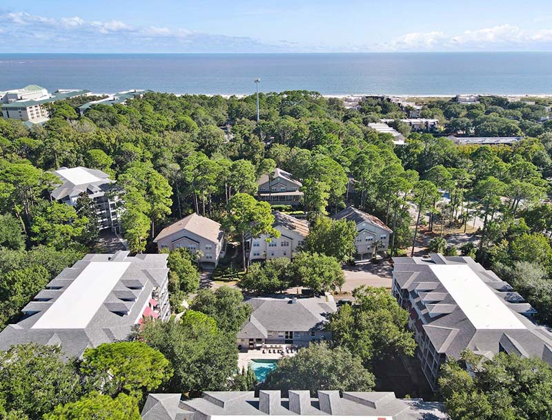 A bird's-eye view of the resort nestled among dense trees, with the ocean visible in the distance.