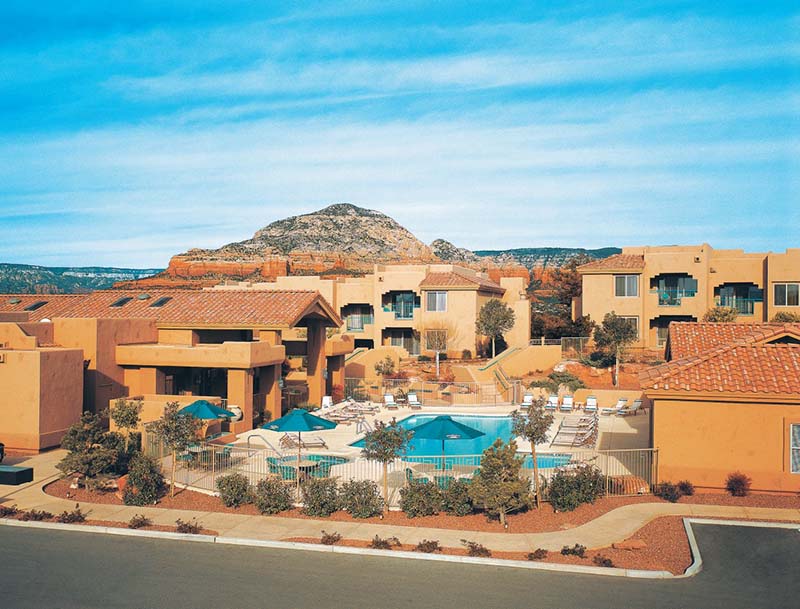 A view of the tranquil pool nestled among the resort buildings, set against a picturesque mountain landscape.