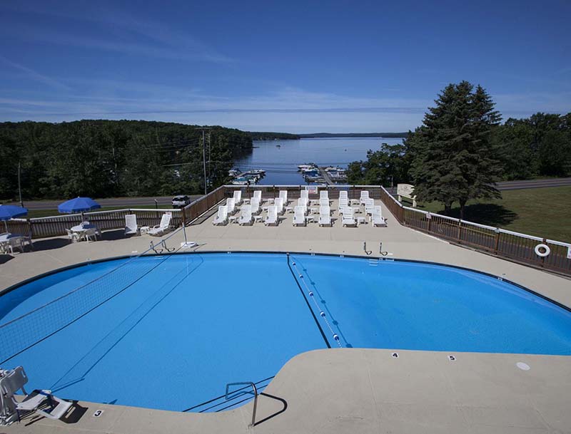 A view of the resort pool and deck area, with a tree lined lake visible in the distance.