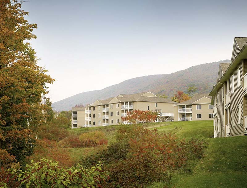 A hillside resort surrounded by lush trees and green grass in a tranquil natural setting.