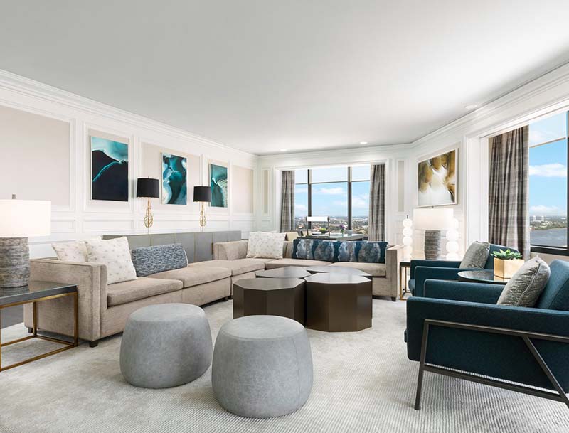 A spacious high-floor hotel room featuring stylish furniture, modern art, and large windows offering picturesque views of the city.