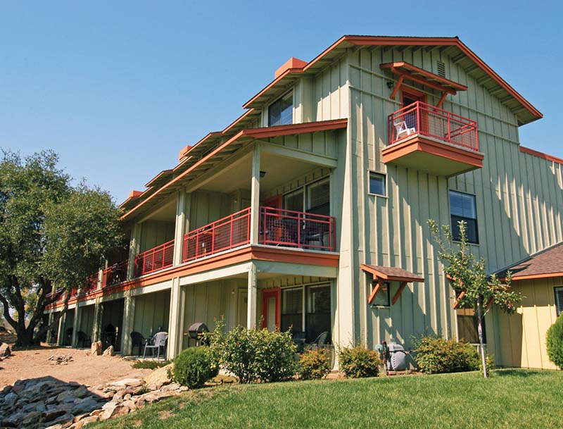 A two-story resort building featuring patios and balconies surrounded by greenery.