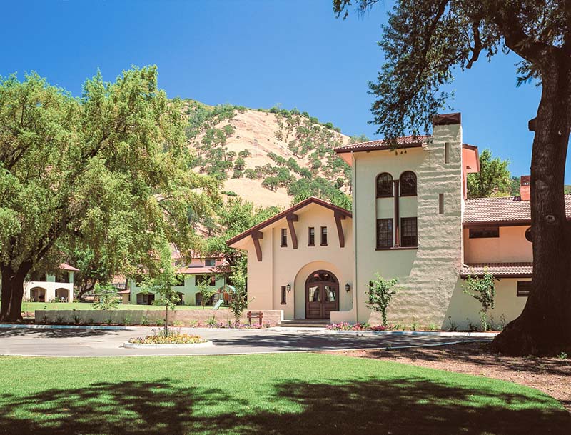 A view of the resort surrounded by large trees and rolling hills in the distance.