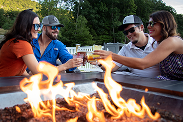 Two couples enjoying drinks by a fire pit