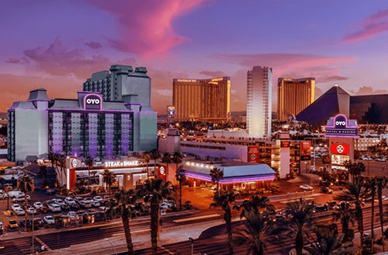 View of OYO Hotel & Casino Las Vegas from across the street with purple lights on the building.