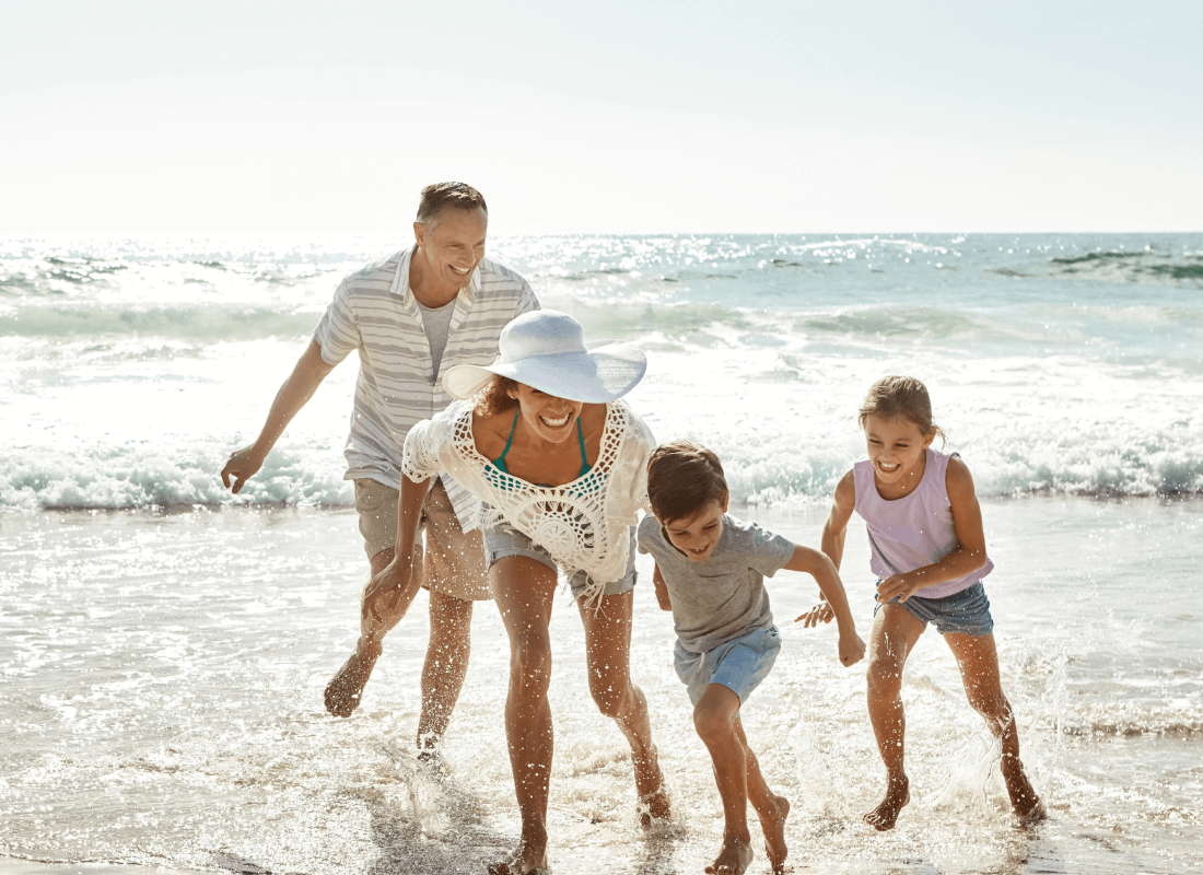 Two adults and two children running on the beach
