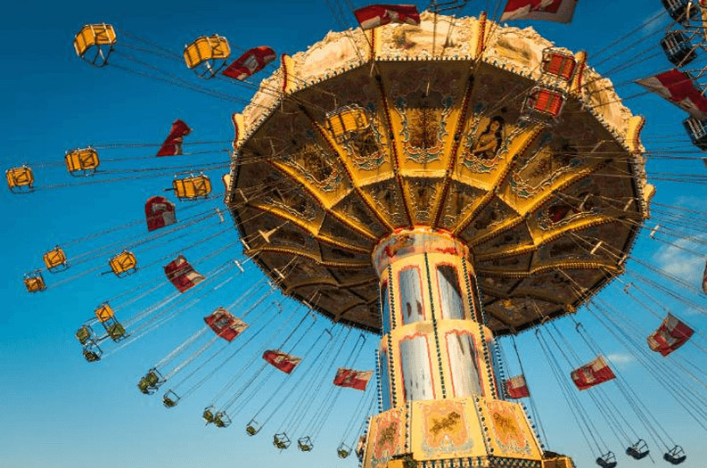 A vibrant flying carousel ride with its seats soaring high above the ground.