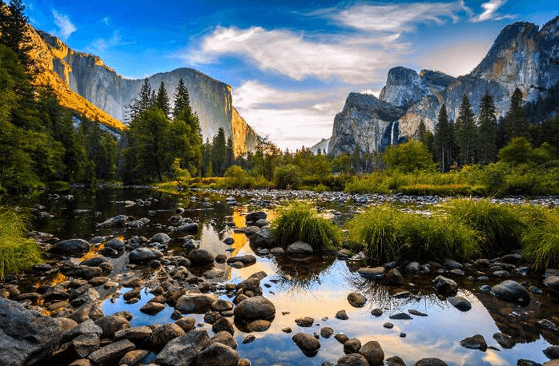 Stunning sunset view of Yosemite Valley, California featuring a tranquil creek and majestic rock formations.