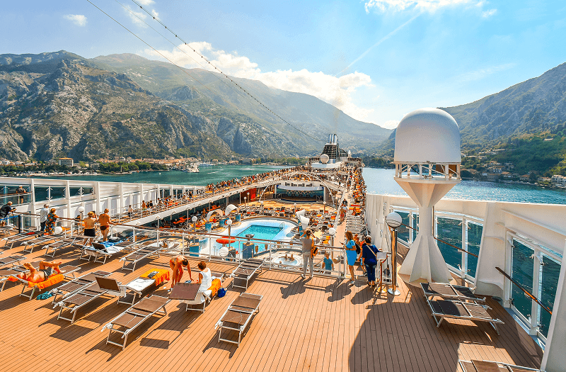Many cruise-goers enjoying the pool deck on a large cruise ship as it heads toward Montenegro on the Adriatic Sea.