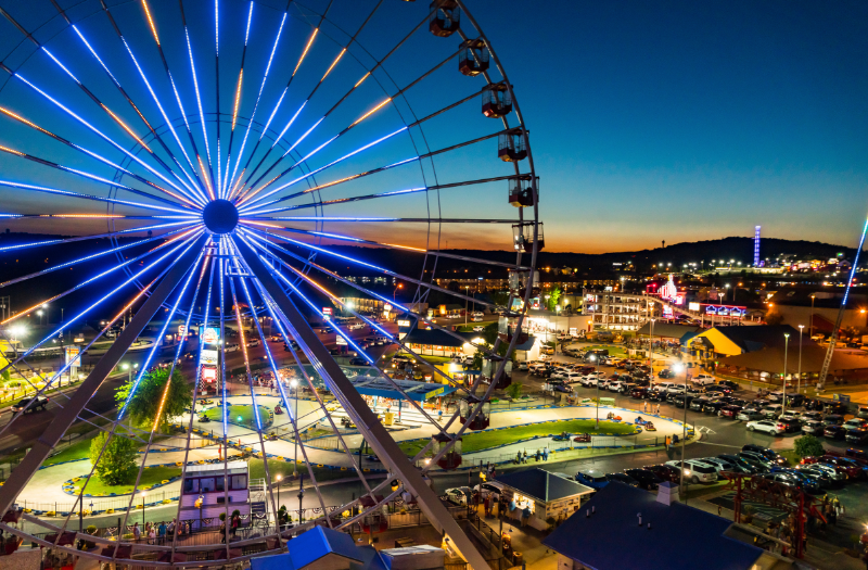 A ferris wheel in Branson at night, adorned with colorful lights, standing out against the evening sky.