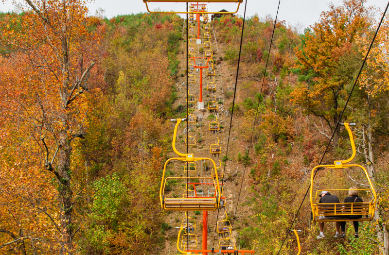 A ski lift with two passengers at Gatlinburg SkyPark, offering panoramic views of the surrounding landscape.