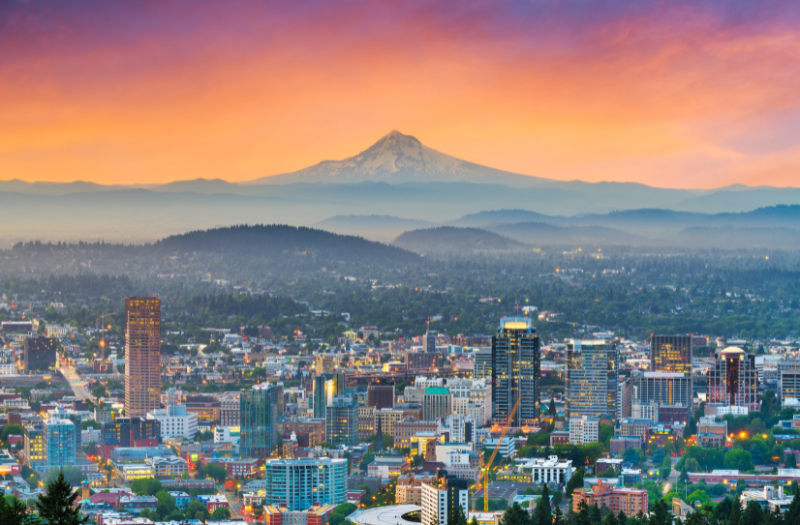 A scenic view of Portland with mountains in the distance and a beautifully colored sky above.